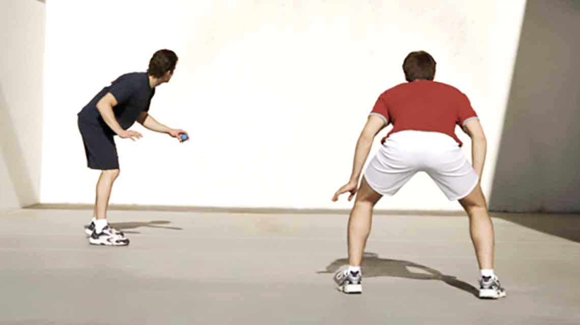 Two men face a wall on a handball court and prepare to start a handball match