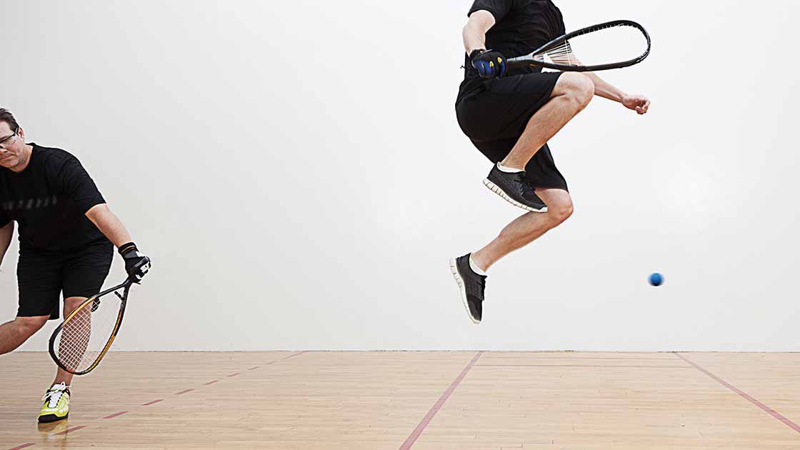 Image of two adults playing racquetball and jumping