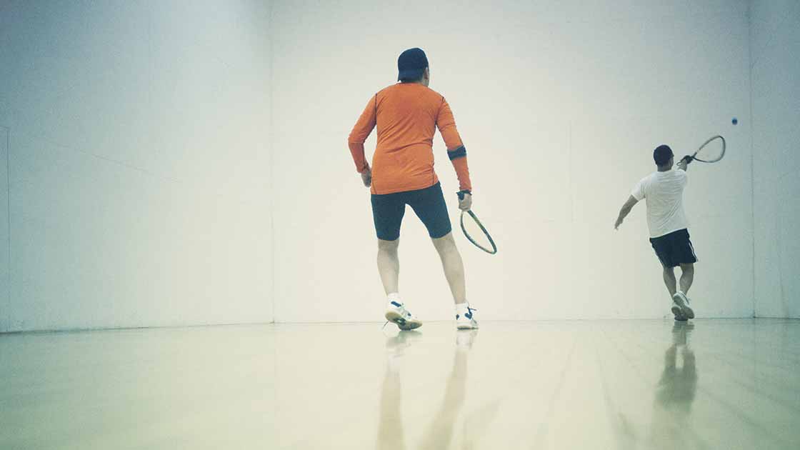 image of two adults playing in a racquetball court