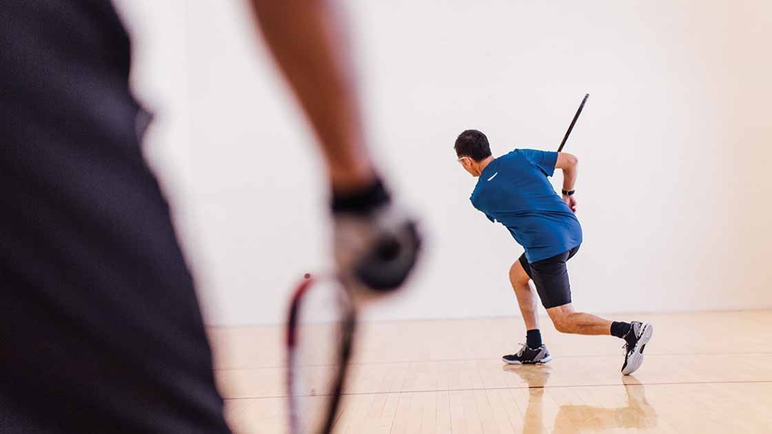 image of two adults playing in a racquetball court