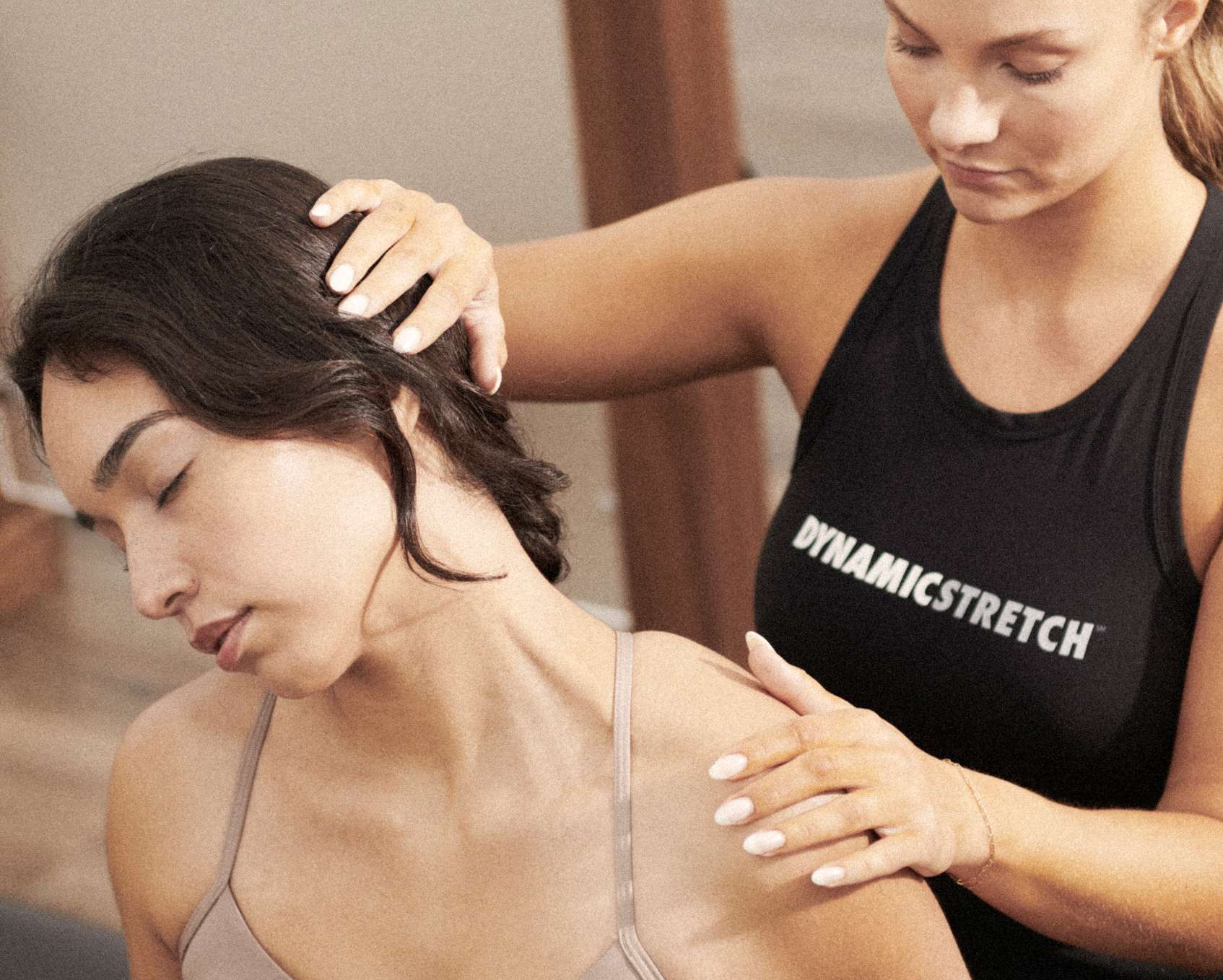 A woman getting her neck stretched by a trainer